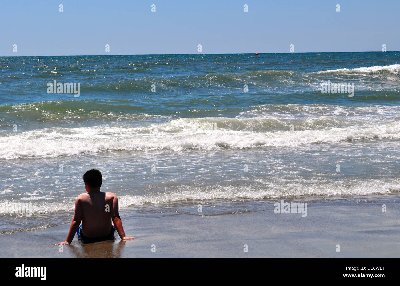 Boy sits on beach Stock Photo