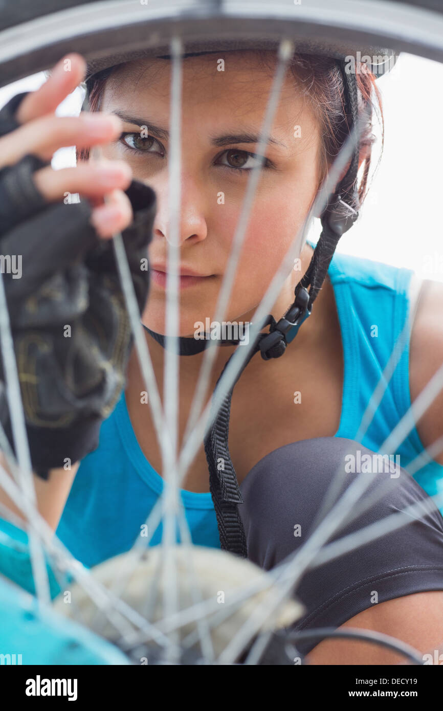 Focused woman adjusting her spokes on bike wheel Stock Photo