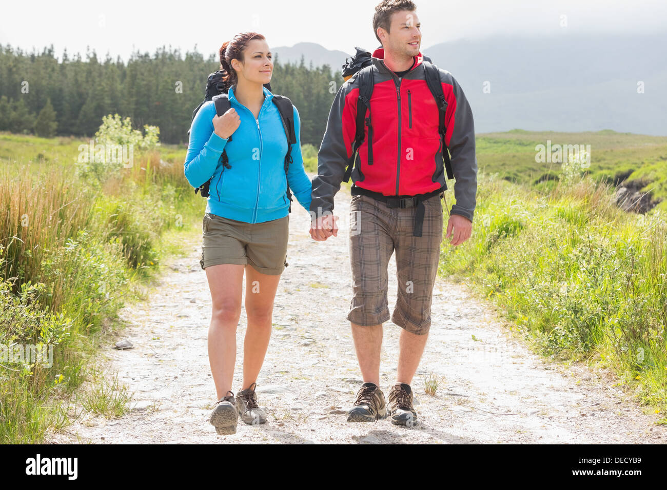Hikers with backpacks holding hands and walking Stock Photo