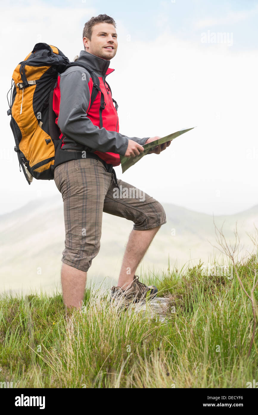 Handsome hiker with rucksack walking uphill holding a map Stock Photo