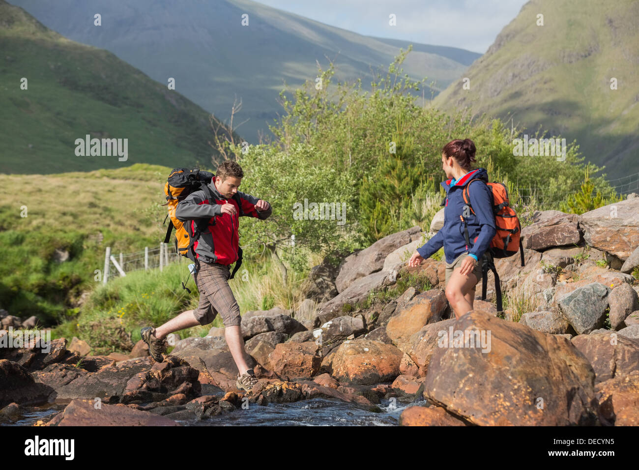 Couple crossing a river on a hike Stock Photo