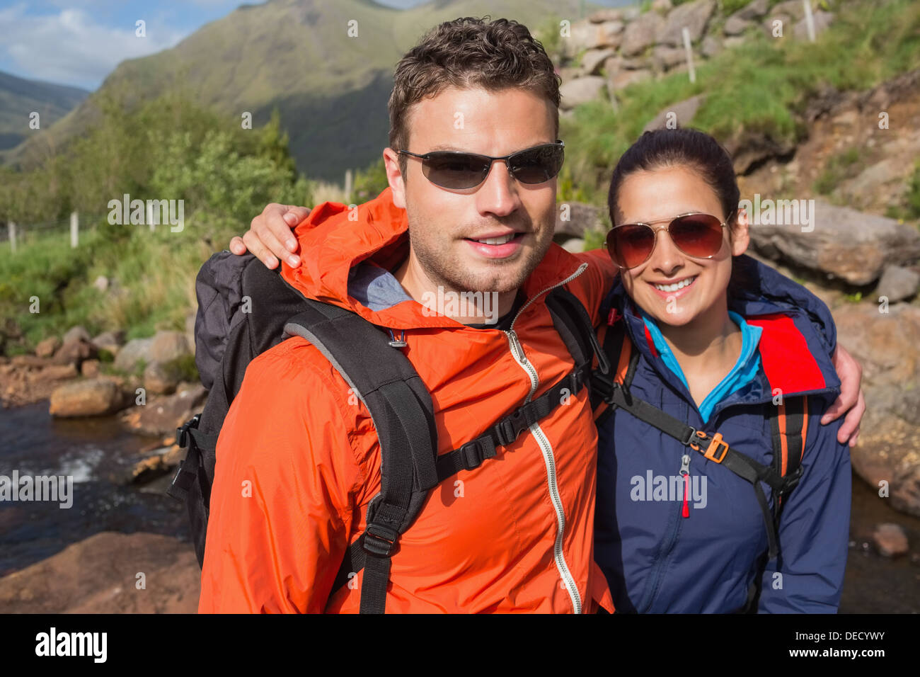 Couple wearing rain jackets and sunglasses smiling at camera Stock Photo
