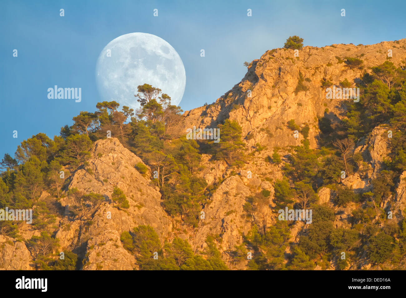 Real full moon rising over Puig des Teix mountain at sunset. Tramuntana mountains, Deia, Majorca, Balearic islands, Spain Stock Photo