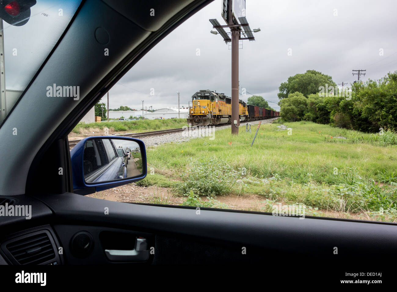 From inside an automobile, an approaching freight train is viewed through the window. Stock Photo