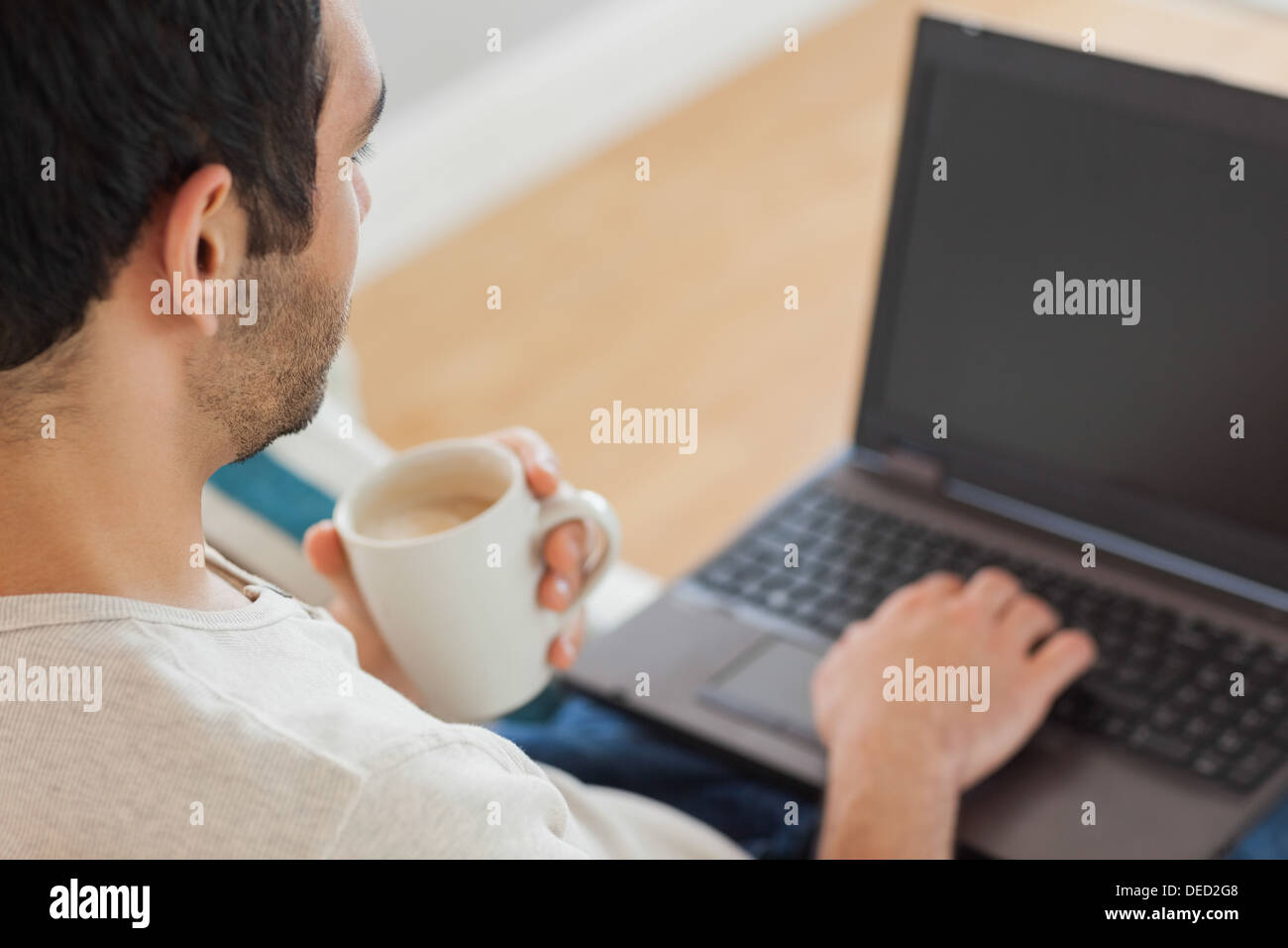 Handsome man drinking coffee while using his laptop Stock Photo