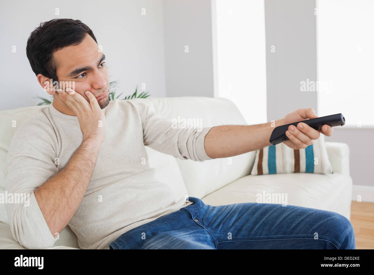 Handsome man getting bored of tv programs Stock Photo