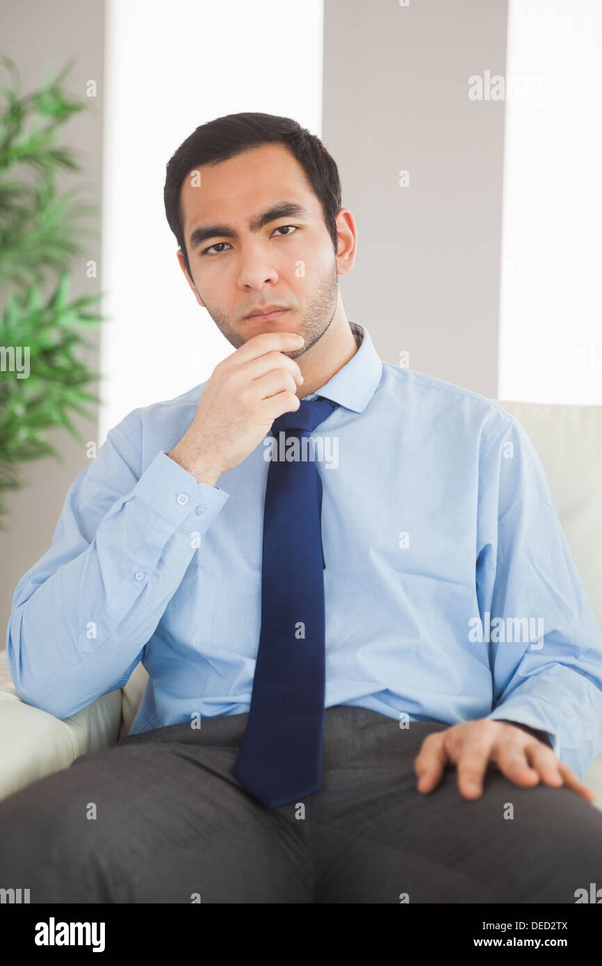 Young classy businessman thinking on cosy sofa Stock Photo