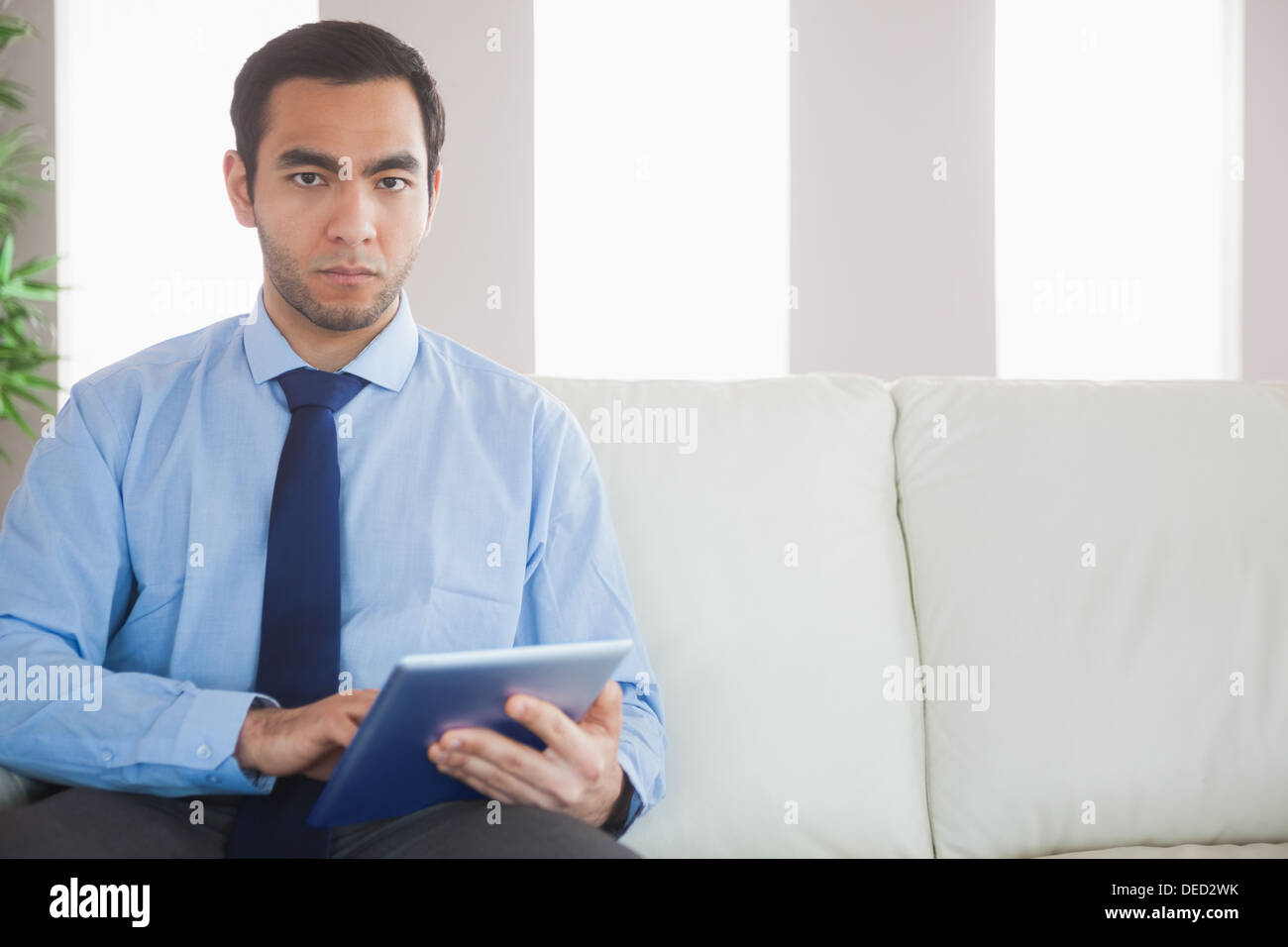 Unsmiling classy businessman using tablet pc Stock Photo
