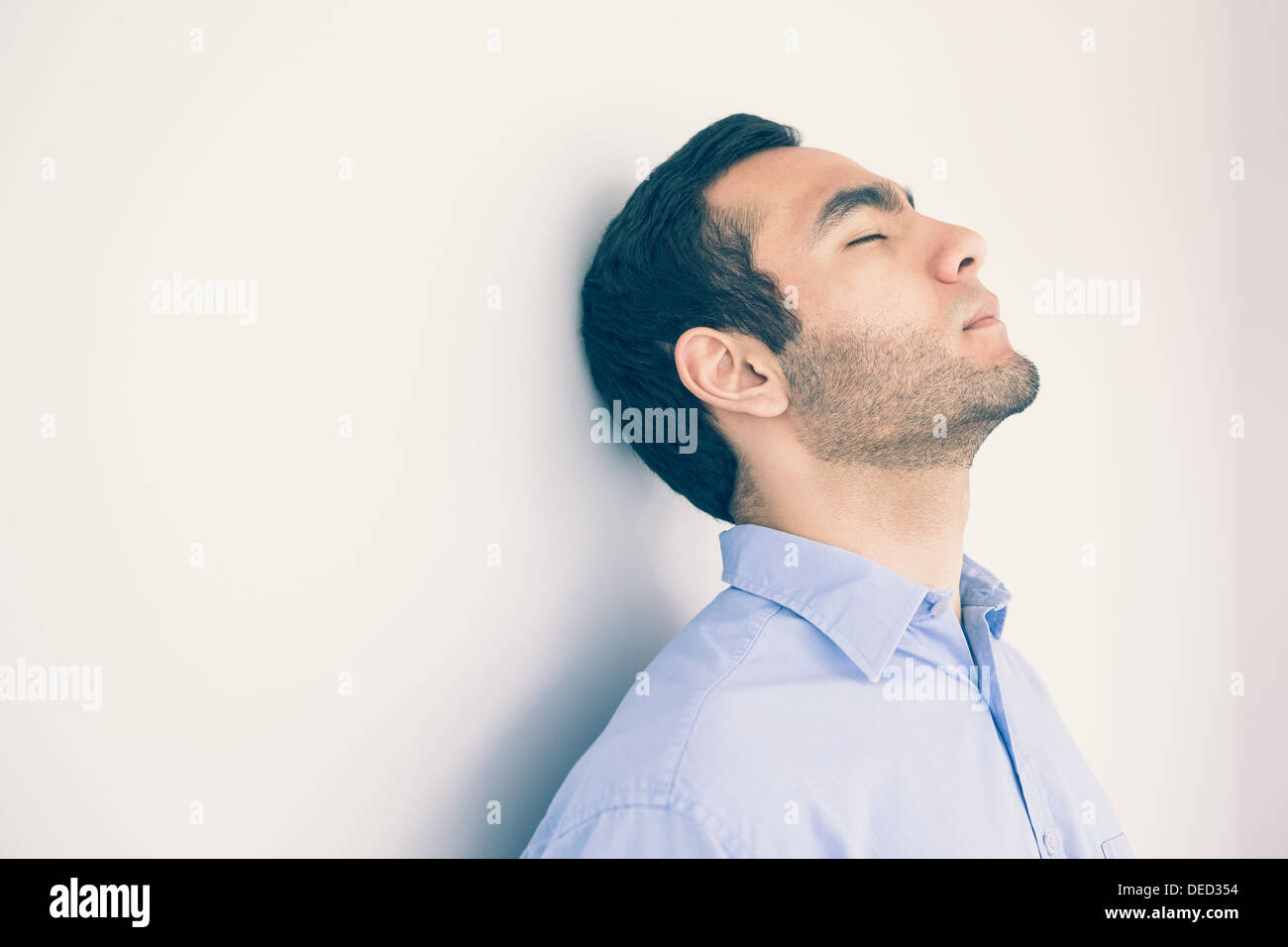 Thoughtful man leaning against a wall Stock Photo