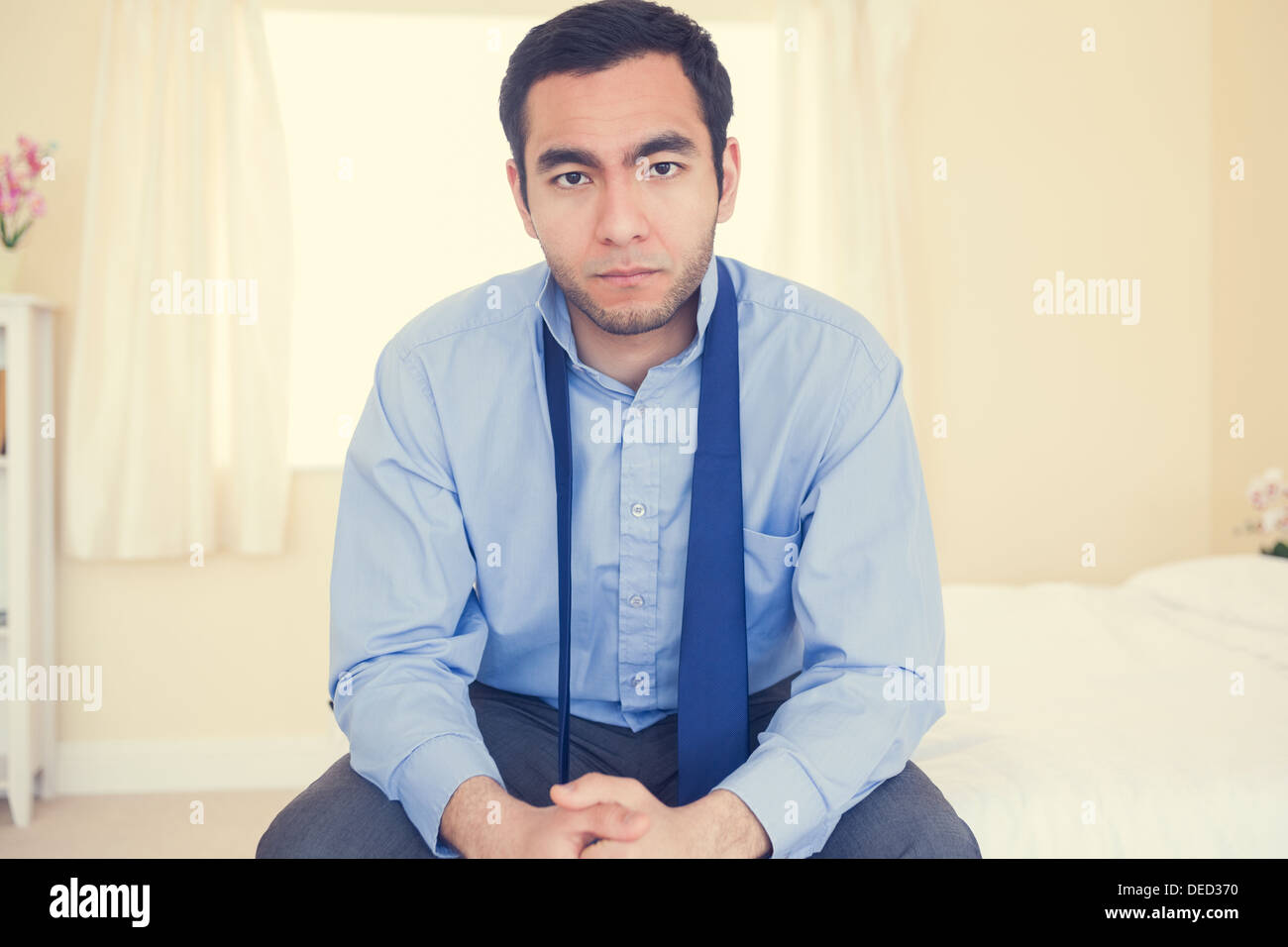 Serious man sitting on his bed Stock Photo