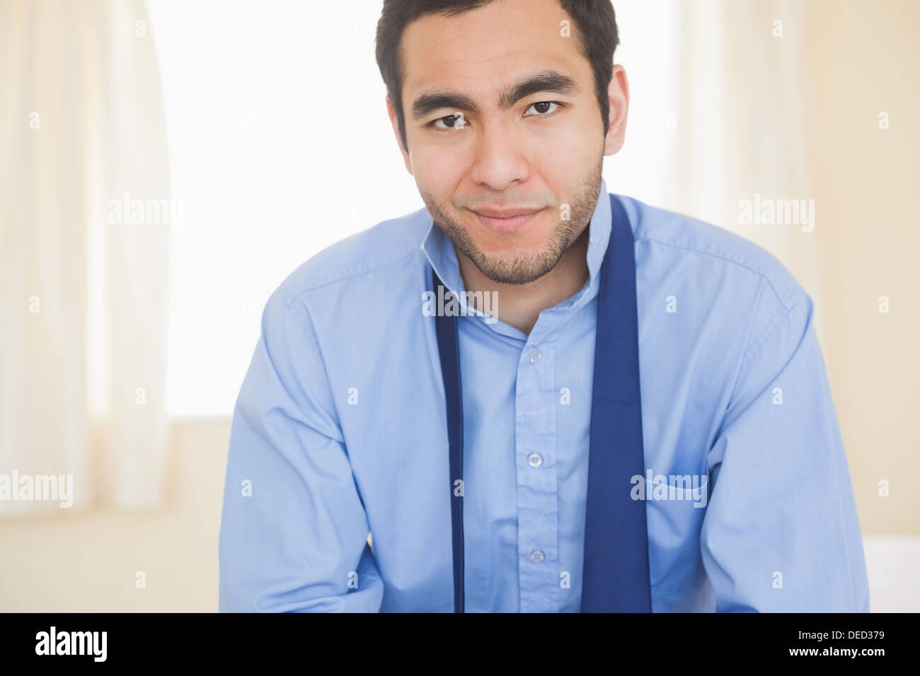 Relaxed man smiling at camera sitting on a bed Stock Photo