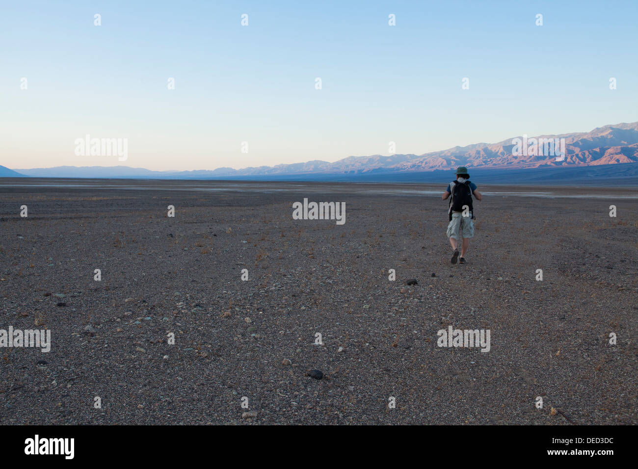 Hiker walking on Death Valley desert dry lake bed Stock Photo