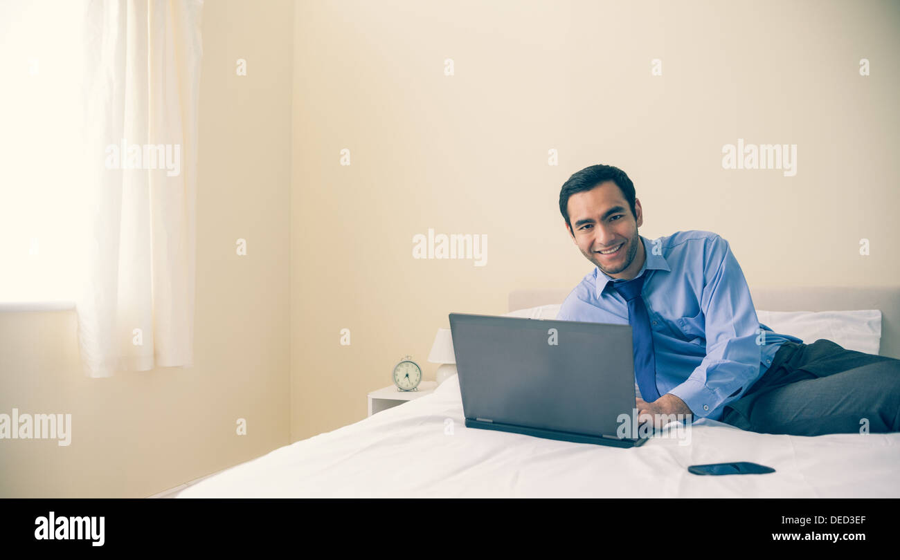 Content man lying on bed using a laptop Stock Photo