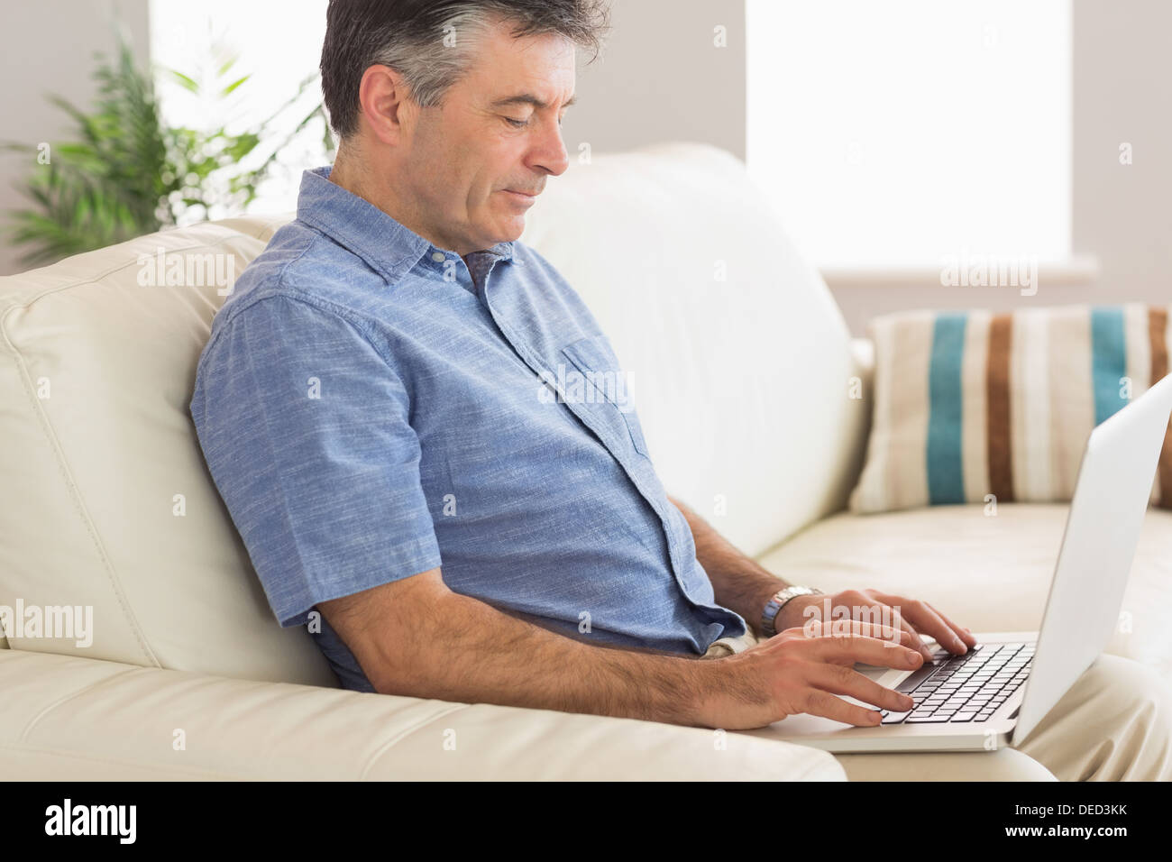 Thinking man sitting on sofa using laptop Stock Photo