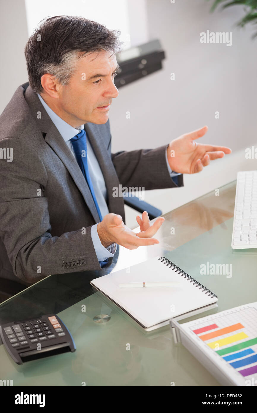 A businessman sitting at his desk explaining something Stock Photo