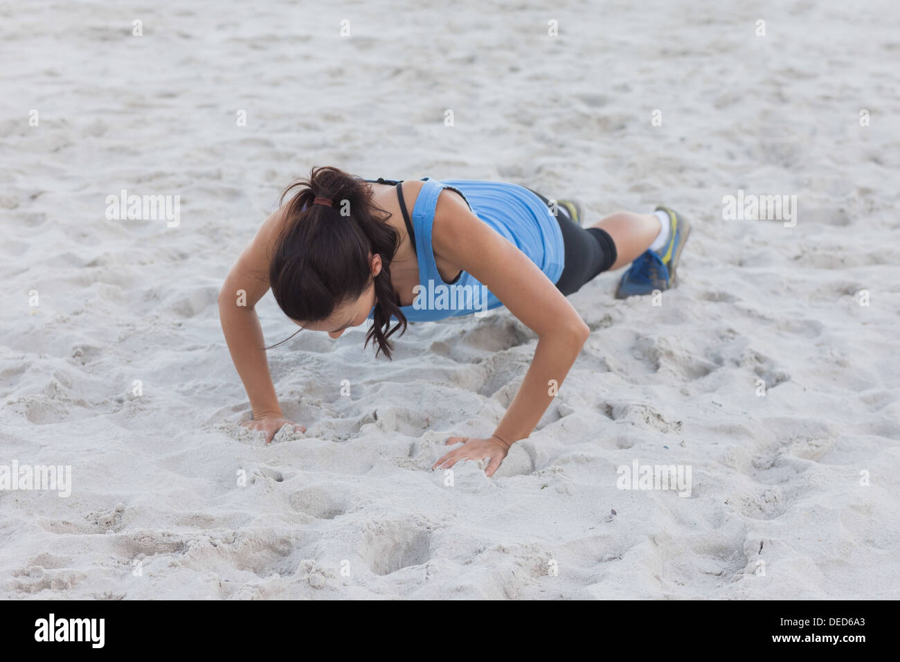 Woman doing push ups at beach Stock Photo
