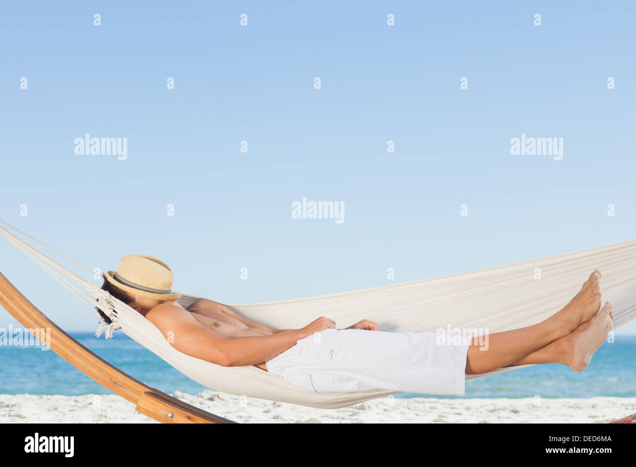Man wearing straw hat relaxing in a hammock Stock Photo
