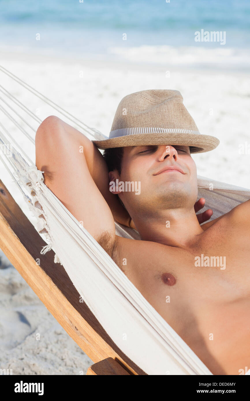 Man wearing straw hat lying in hammock Stock Photo