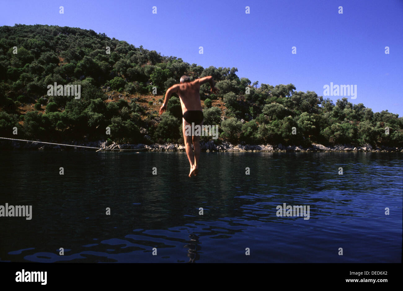 A man jumping into the water in Marmaris along the shoreline of the Turkish Riviera southwest Turkey Stock Photo