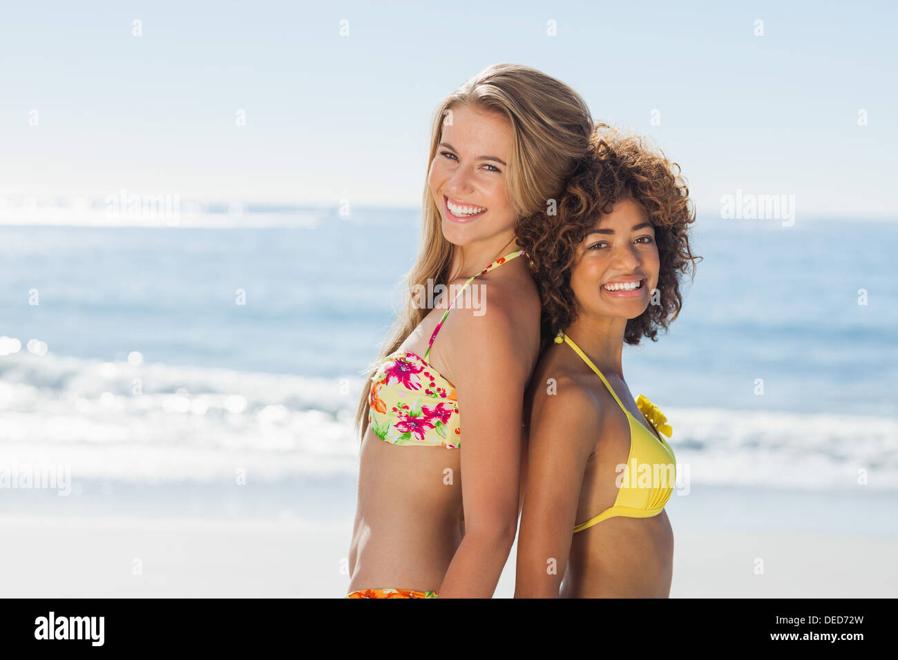 Smiling friends in bikinis standing back-to-back Stock Photo
