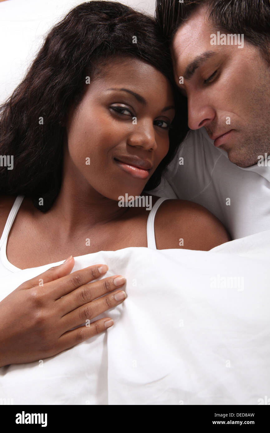 Mixed couple laying in bed Stock Photo