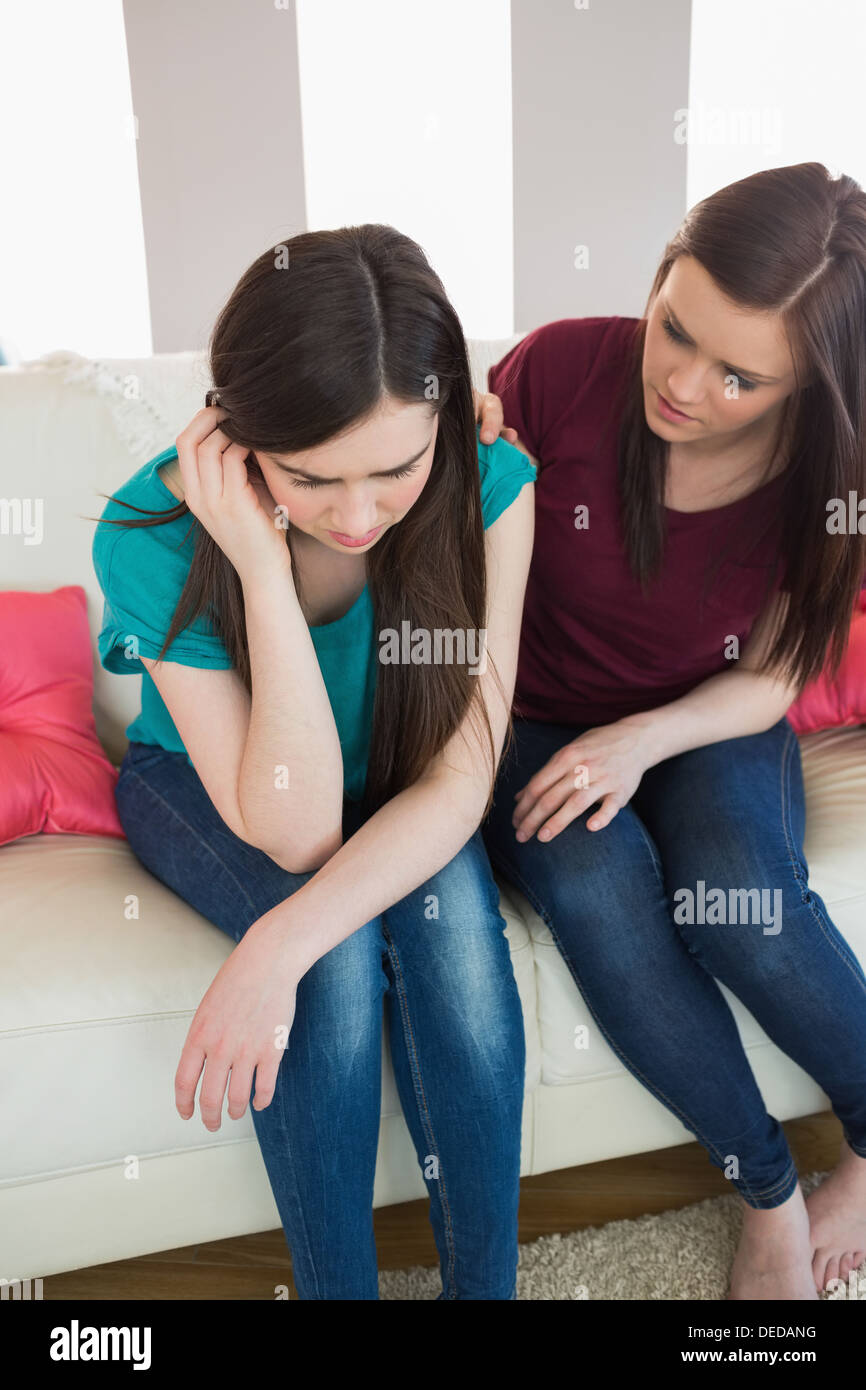 Girl comforting her upset crying friend on the couch Stock Photo