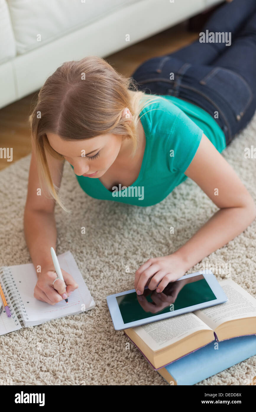 Focused young woman lying on floor using tablet to do her assignment Stock Photo