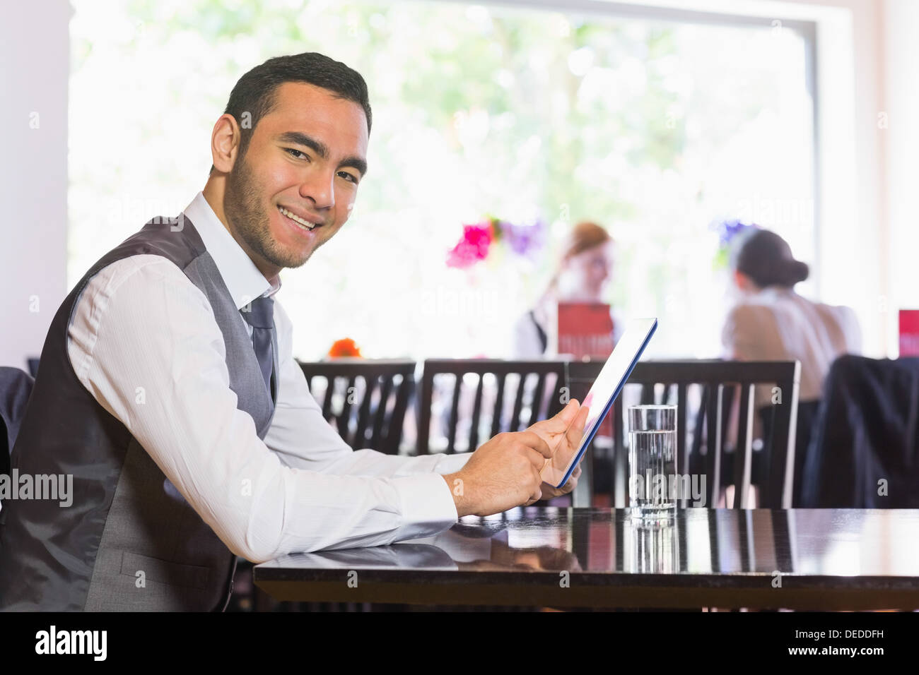 Happy businessman using tablet and smiling at camera Stock Photo
