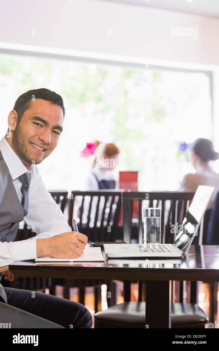 Happy businessman writing while smiling at camera Stock Photo
