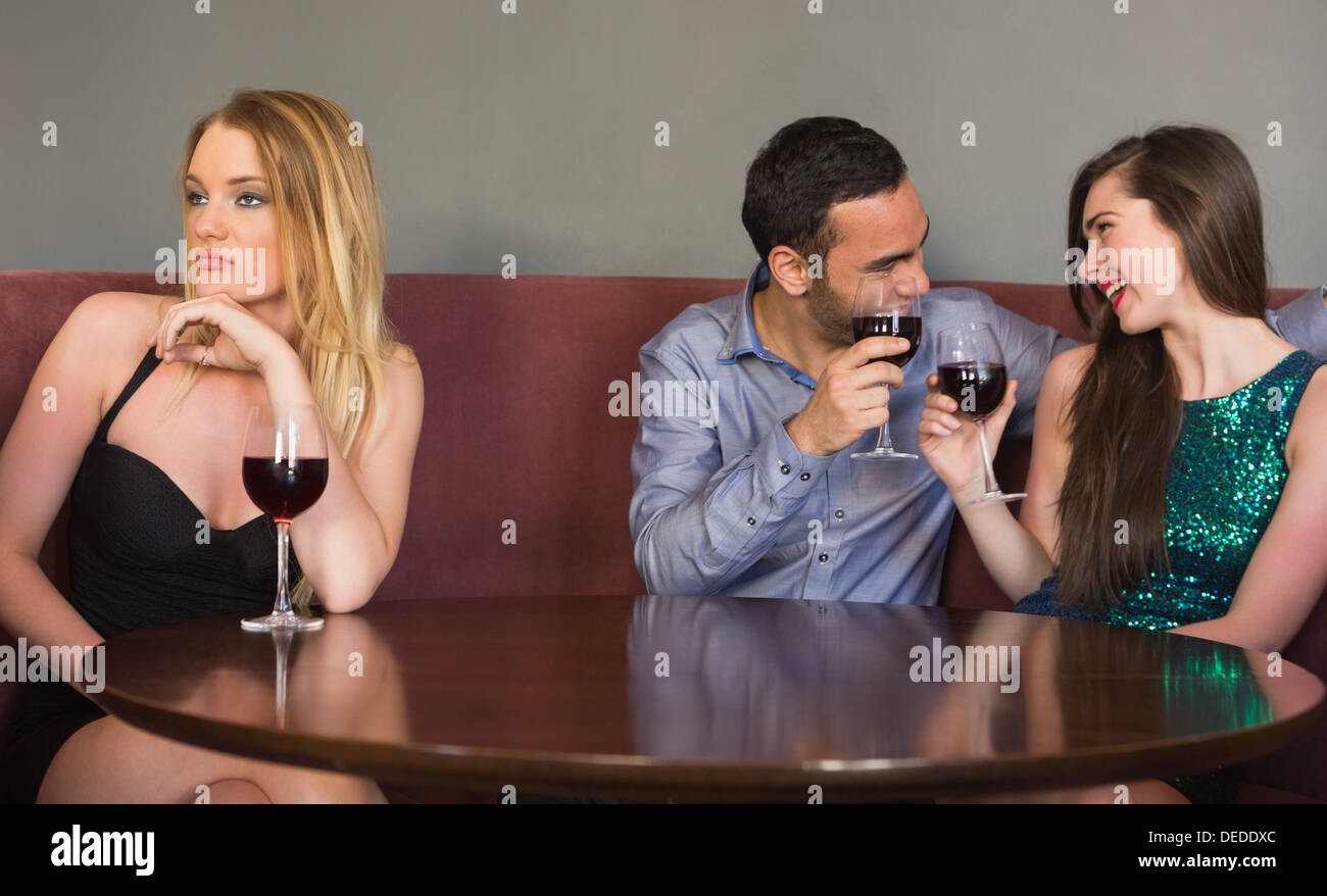 Blonde woman feeling alone as two people are flirting beside her Stock Photo