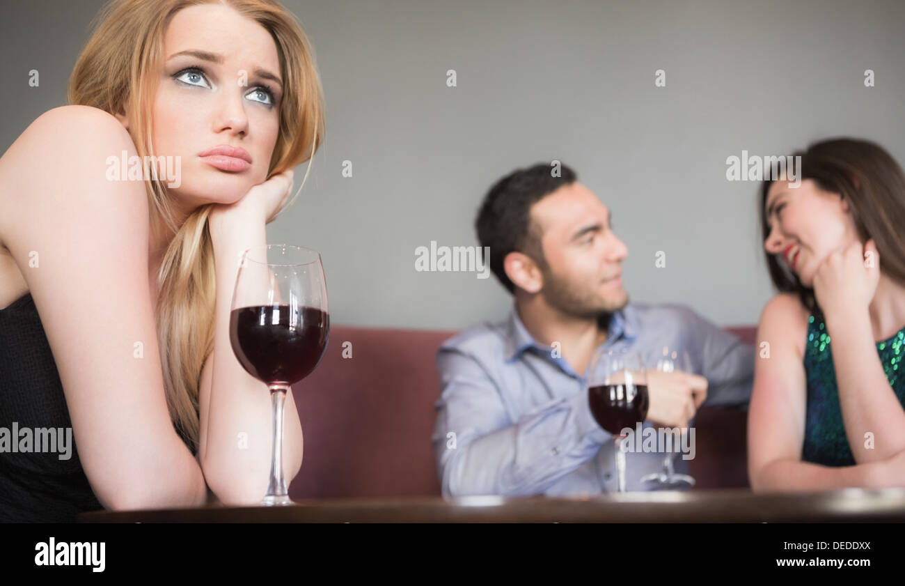 Blonde woman feeling jealous of couple flirting beside her Stock Photo