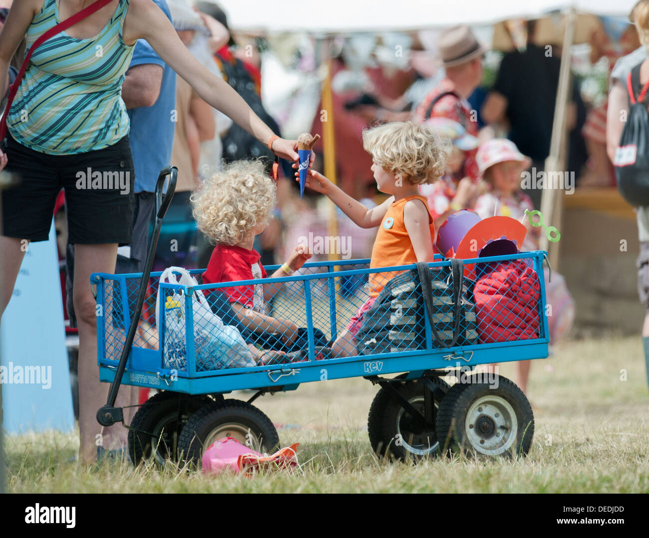 Two young boys in a trolley are handed ice creams at the Wilderness Festival at Cornbury Park, Oxfordshire 2013 Stock Photo