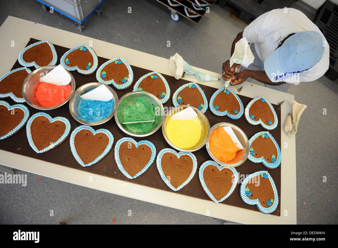 An employee of the company Zuckersucht decorates gingerbread hearts in Aschheim near Munich, Germany, 06 September 2013. The company is the biggest gingerbreas heart producer for the Oktoberfest. During peak times, like before the Wiesn, the company produces 40,000 gingerbread hearts a day. The complete production is handwork. Photo: ANDREAS GEBERT Stock Photo