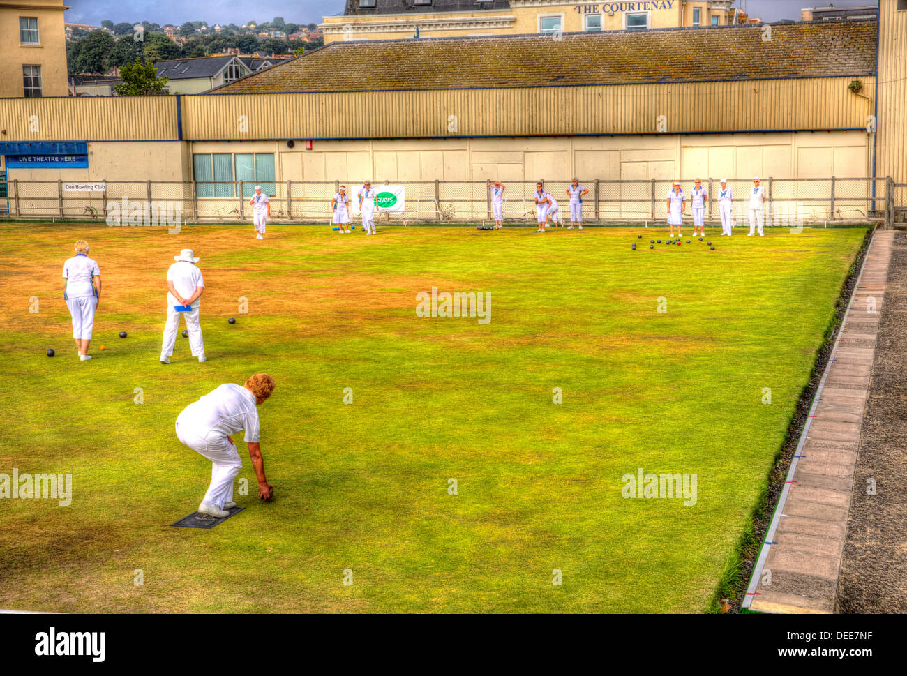 Women playing bowls summer day with blue sky and white clouds in HDR, English game played on green lawn Stock Photo