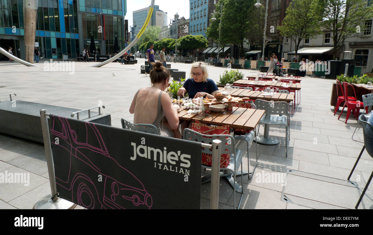 Two young women eating foodoutside Jamie's Italian restaurant in Cardiff City Centre Wales UK  KATHY DEWITT Stock Photo