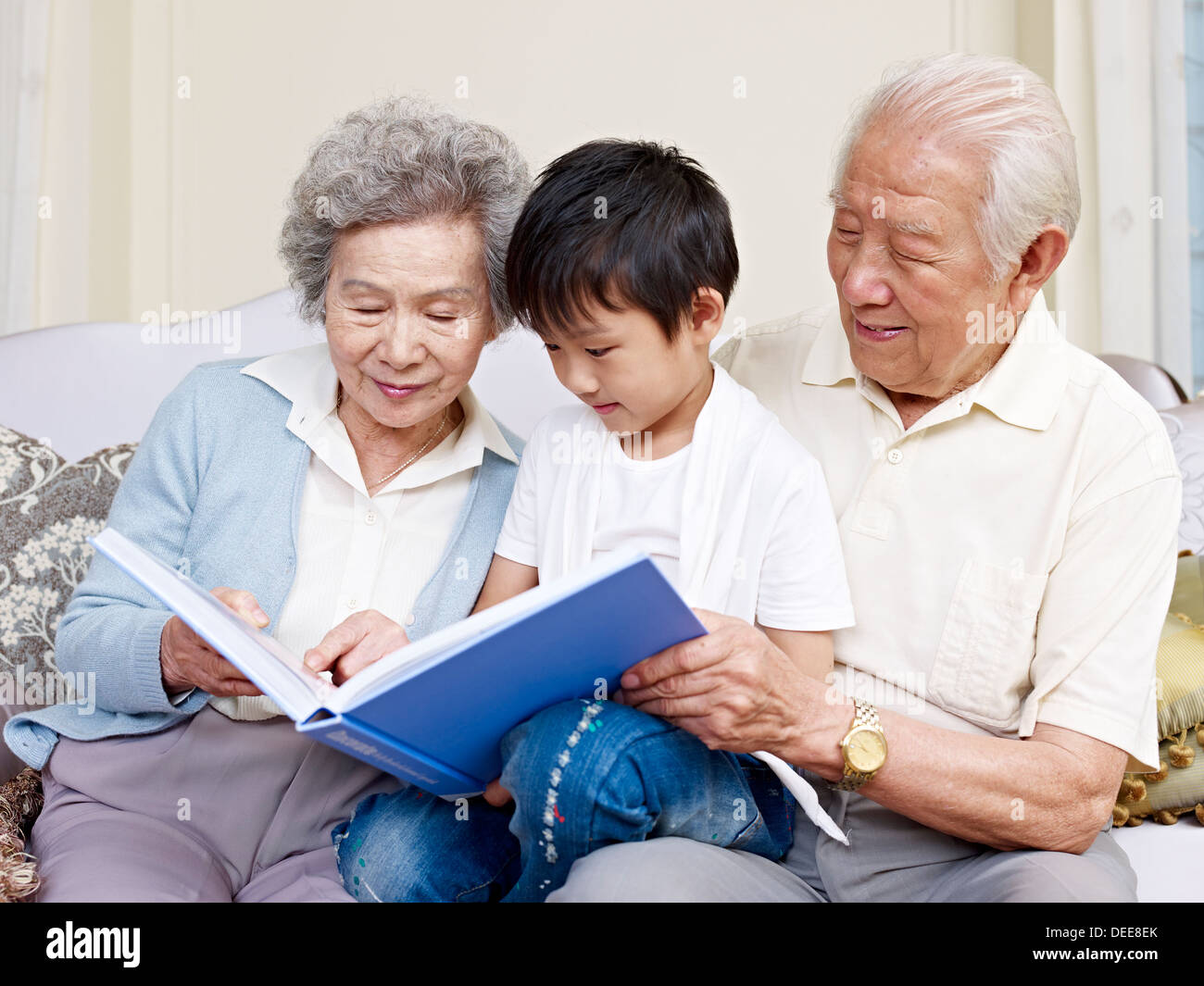 grandparents and grandson reading a book together. Stock Photo
