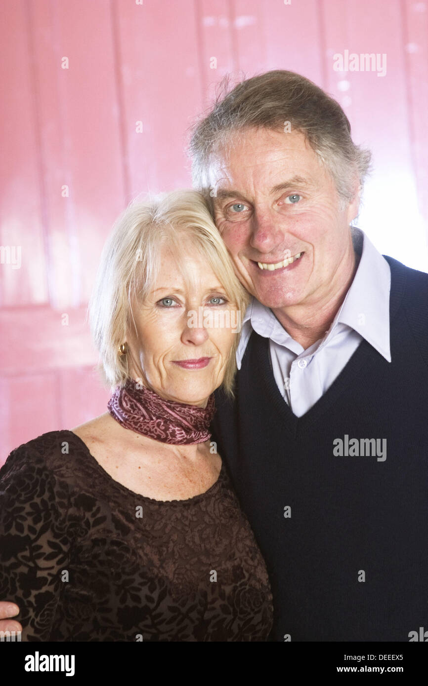 56-year-old-couple-standing-together-smiling-into-camera-stock-photo