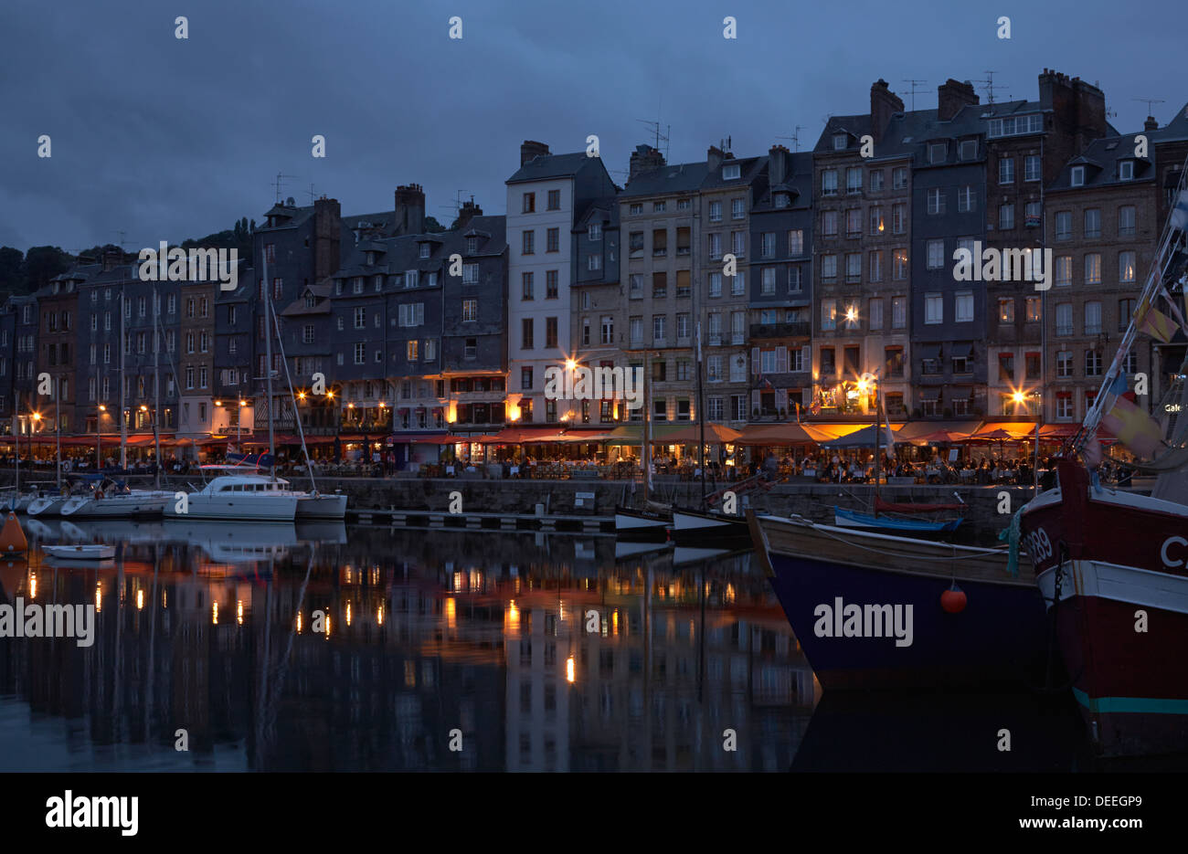 Evening in Honfleur harbour with restaurant lights and reflections ...