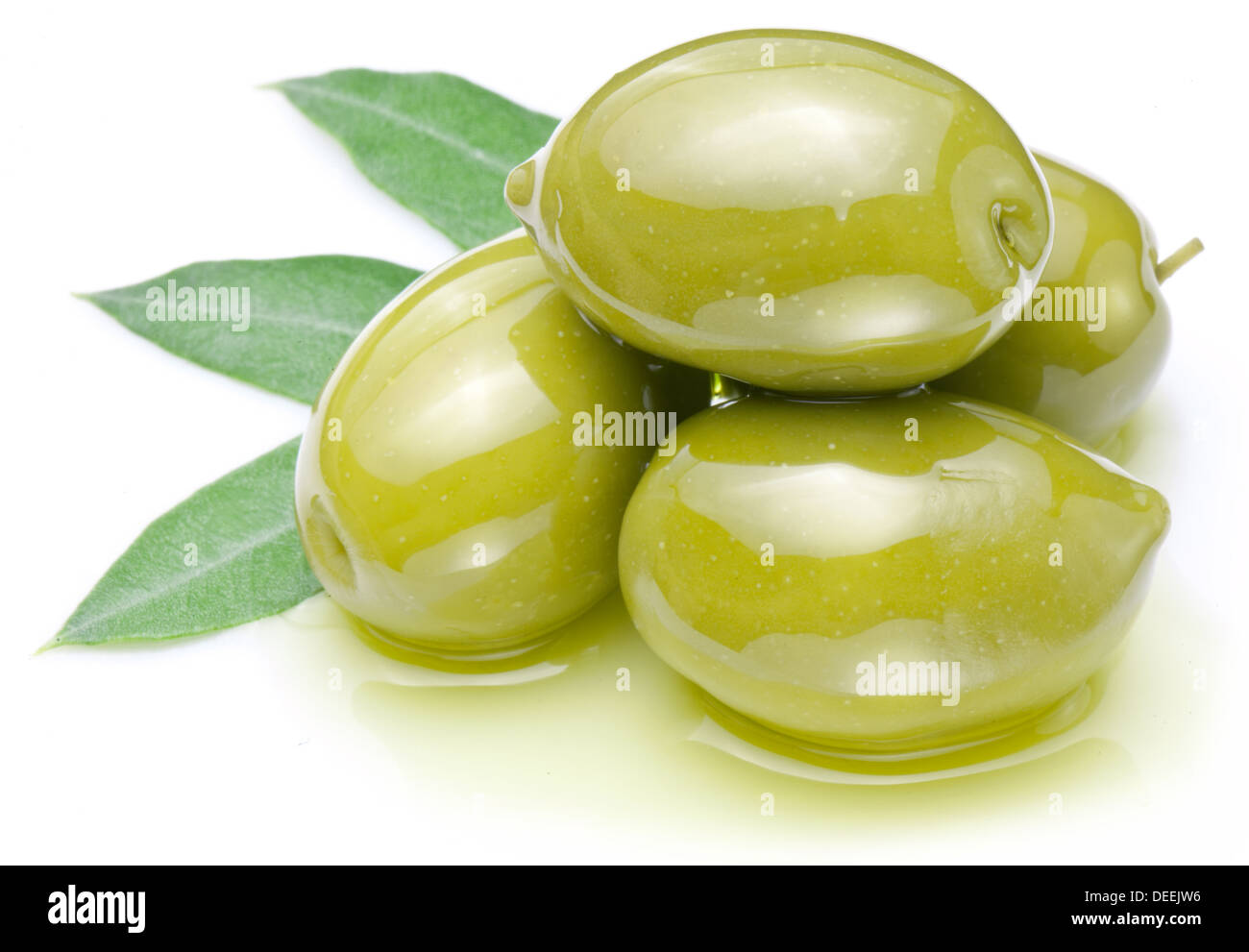 Green olives with leaves in oil isolated on a white. Stock Photo