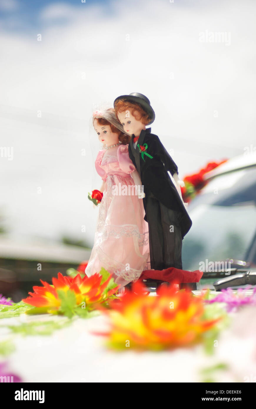 Miniature smart couple based on front car ready for wedding with flowers on their feet Stock Photo