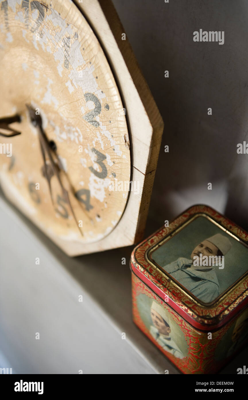 Salvaged clock and tin on grey plasterwork shelf, Morocco Stock Photo