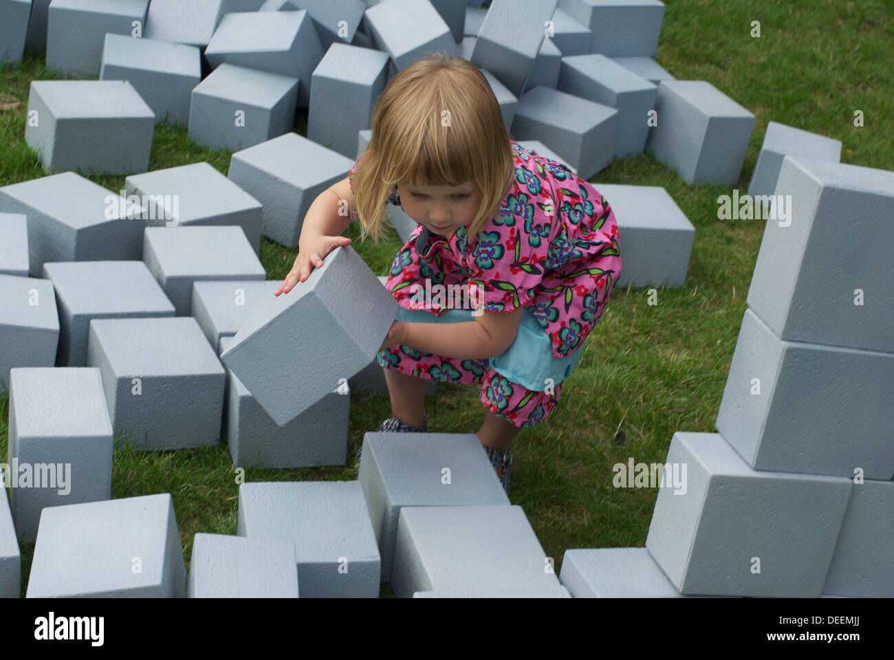 young girl playing outside with building blocks Stock Photo