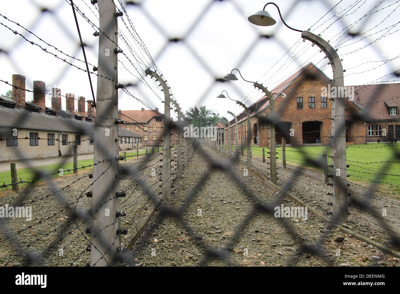 Looking though barbed wire electric fences, prisoner huts where Jews were kept before going to the gas chambers. Stock Photo