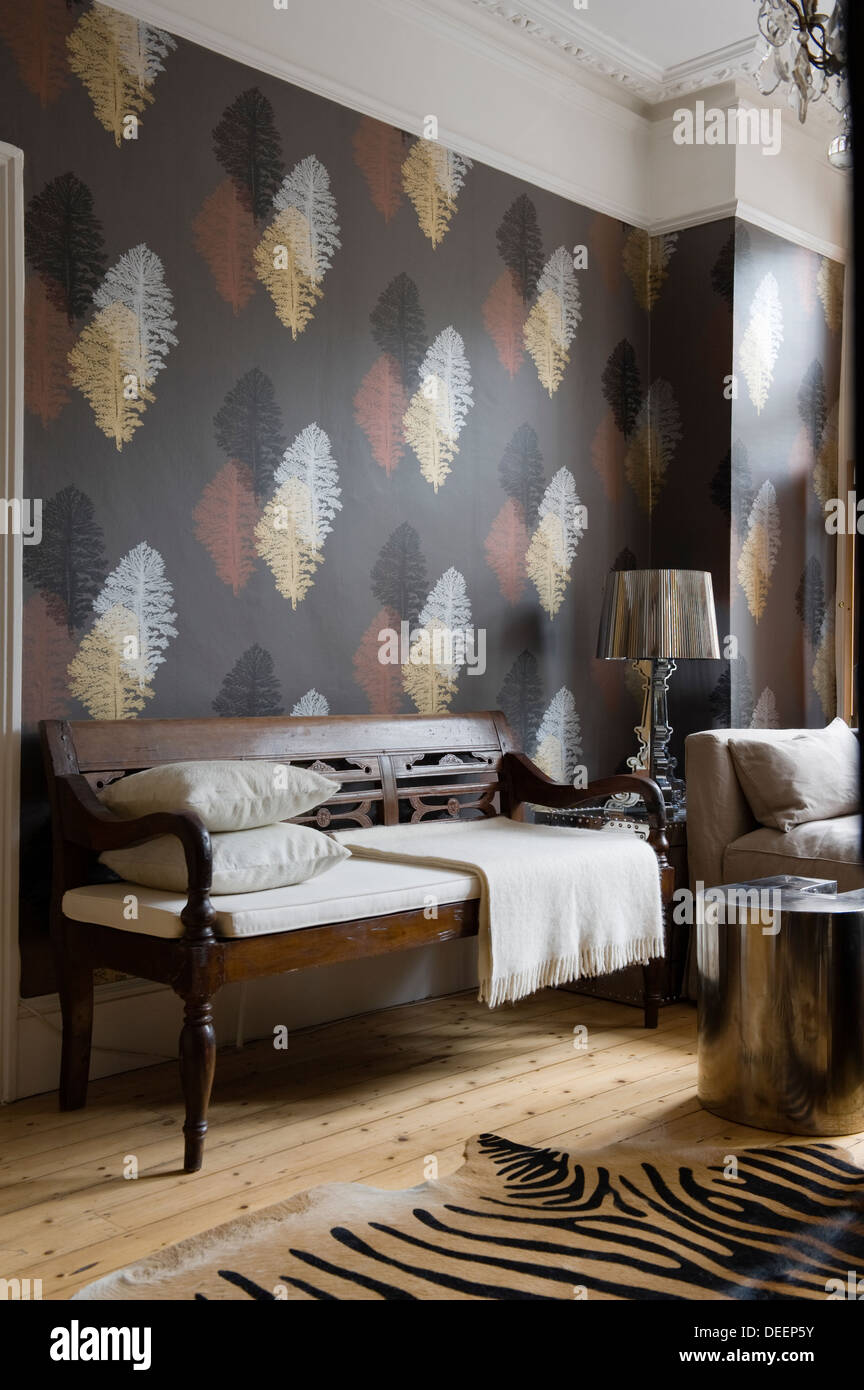 Leaf motif wallpaper with metallic accents in eclectically furnished living area Stock Photo