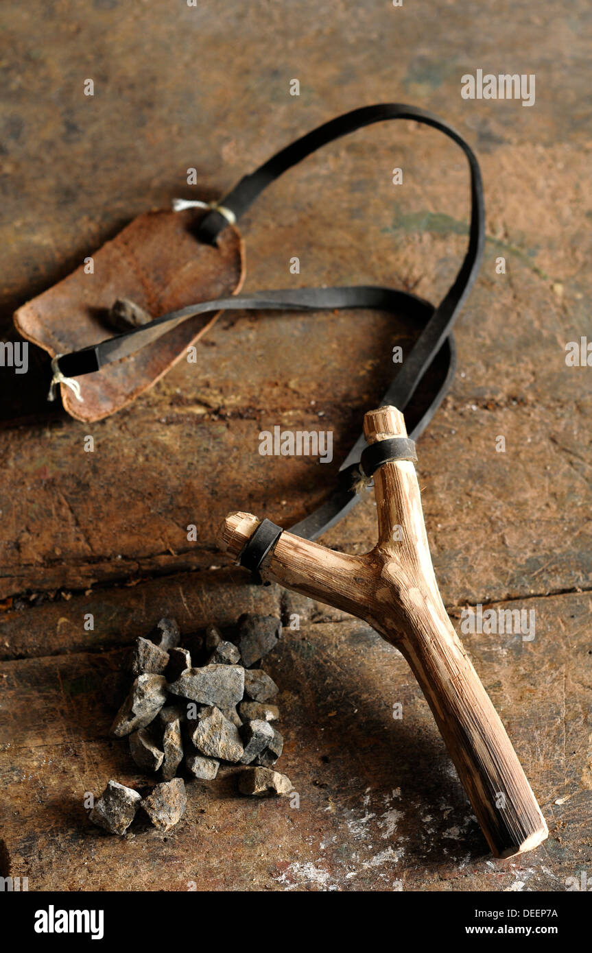 old wooden slingshot and stone on wooden table Stock Photo