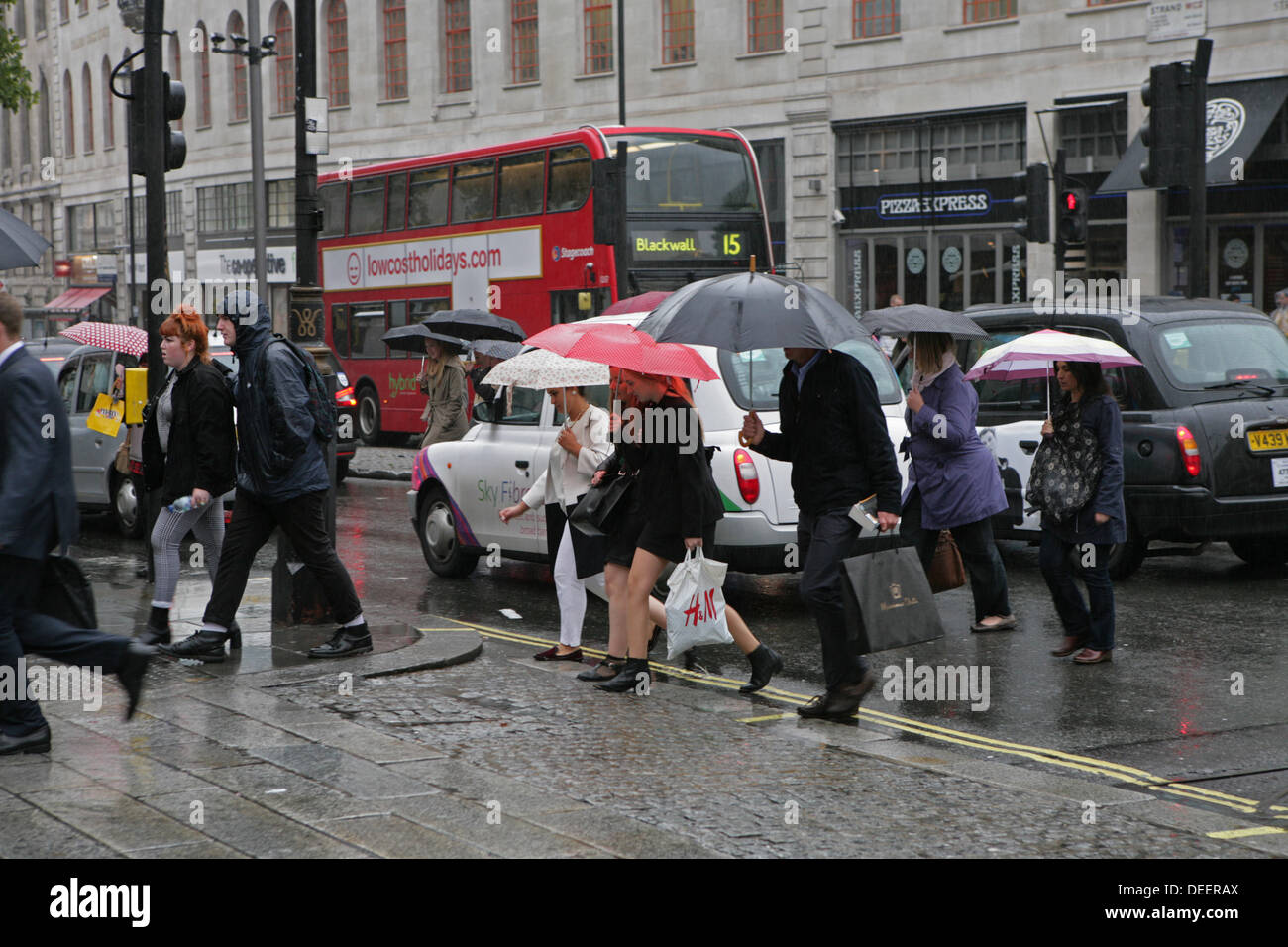 London, UK. 17th September 2013. People rushing across the road with umbrellas up to get out of