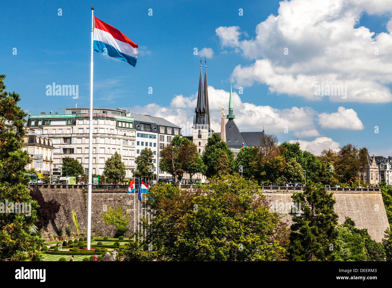 View over the Petrusse Valley Park to the Grand Hotel Cravat and Notre-Dame Cathedral. Luxembourg flag flies against a blue sky. Stock Photo