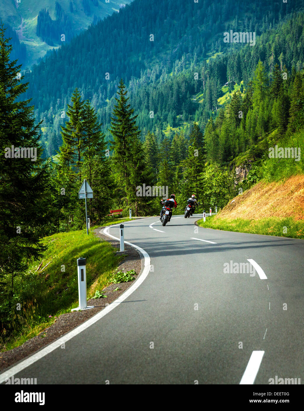 Group of motorcyclists in Alpine mountains, motor racers on curve ...