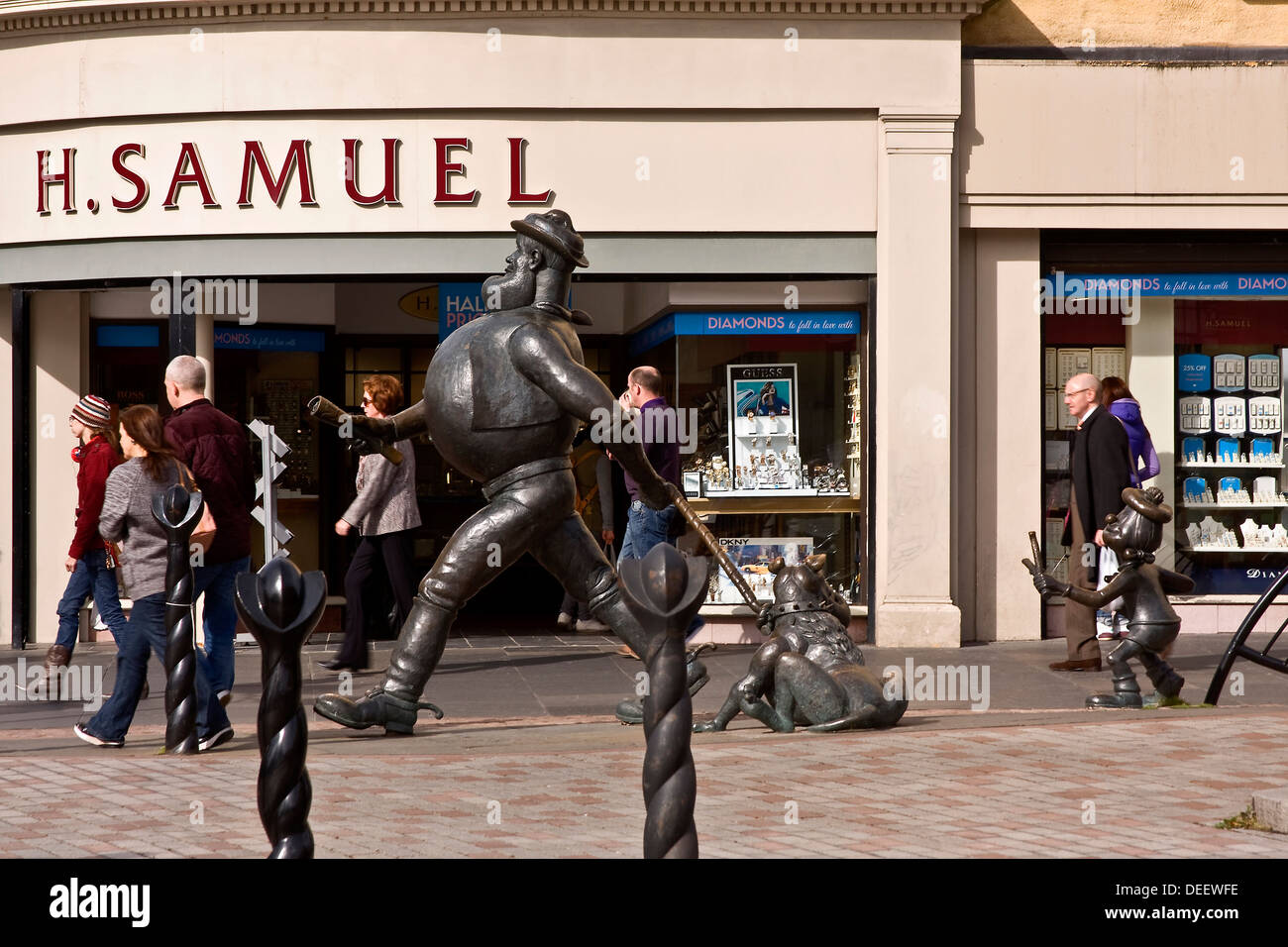 Desperate Dan striding along the street outside H Samuel Jewelers retail store in Dundee; UK Stock Photo