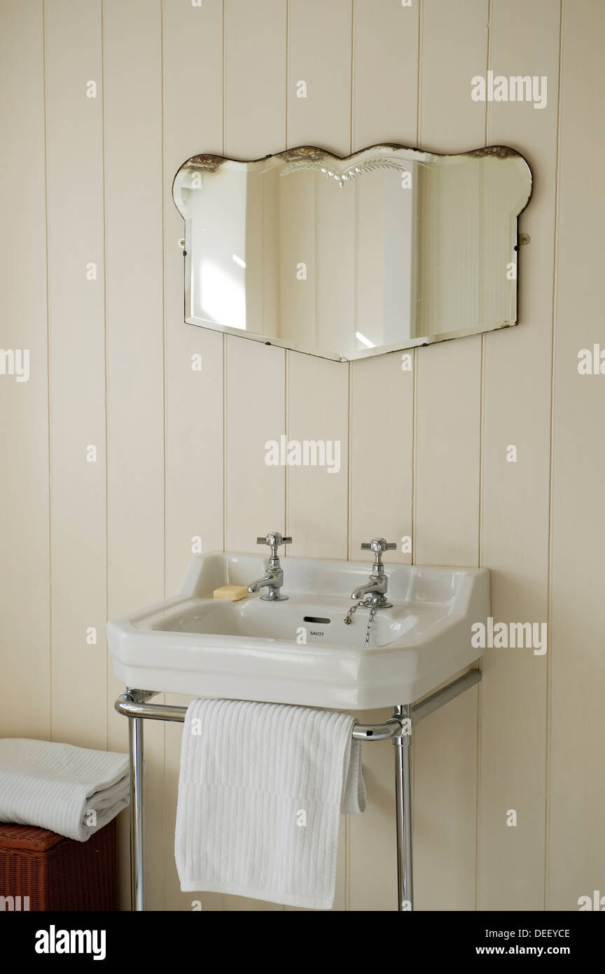 Vintage mirror on paneling above wall mounted wash basin Stock Photo